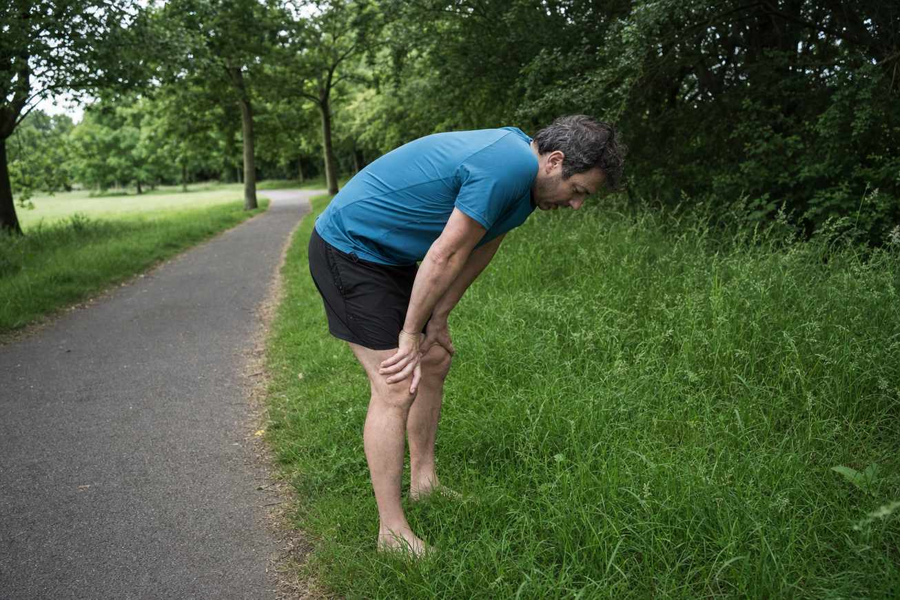 A runner pausing for a break at the side of a quiet park path