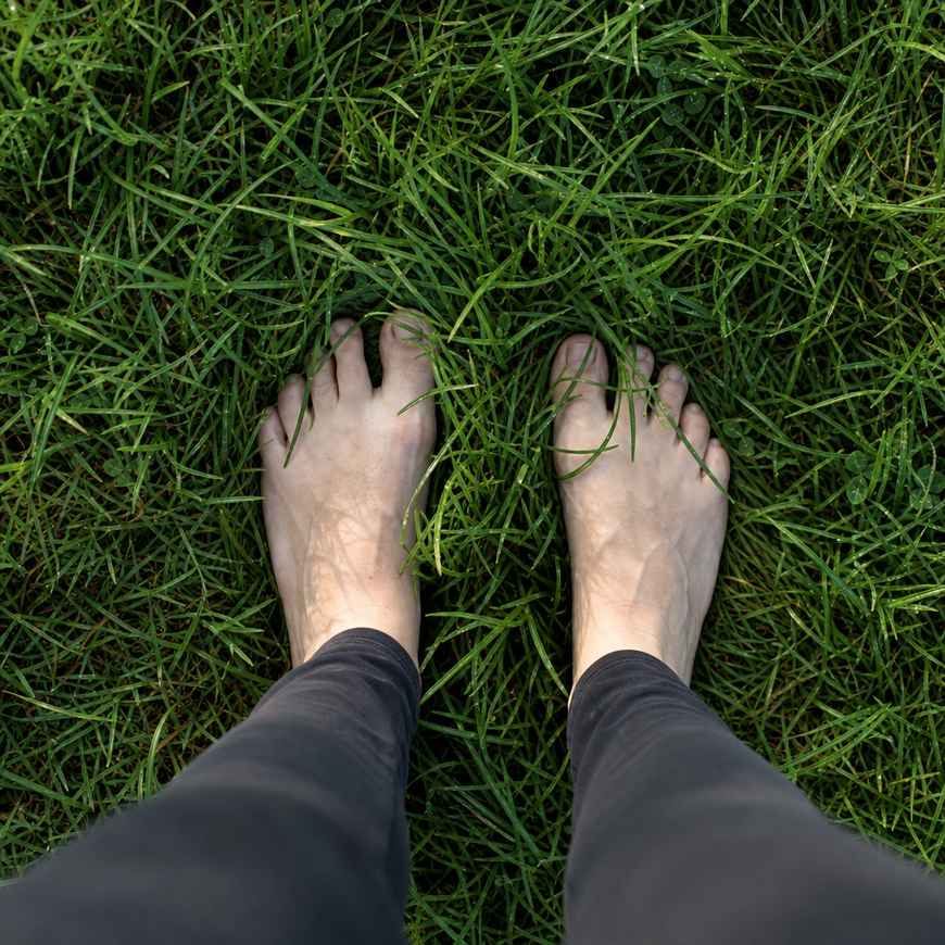 Bare feet standing on dewy green grass seen from above