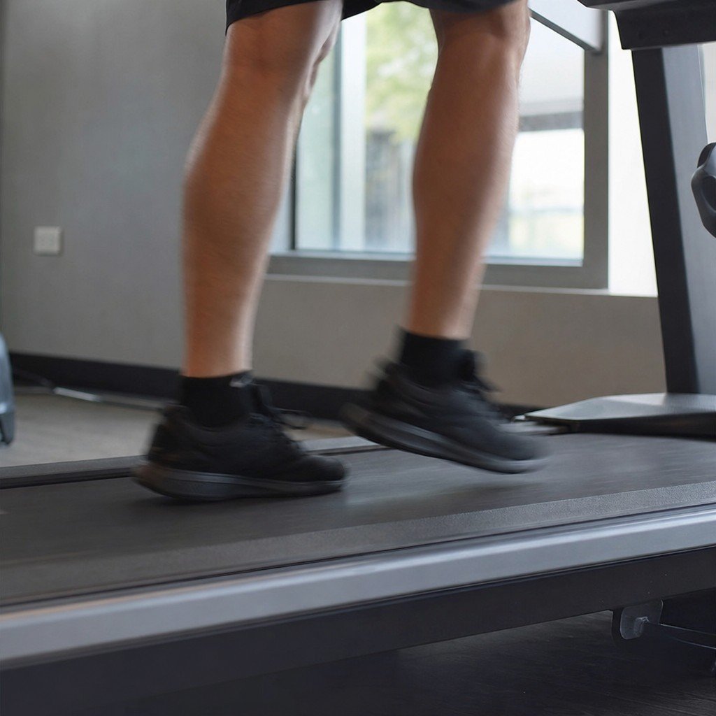 Low side view of a person's legs jogging on a moving treadmill belt